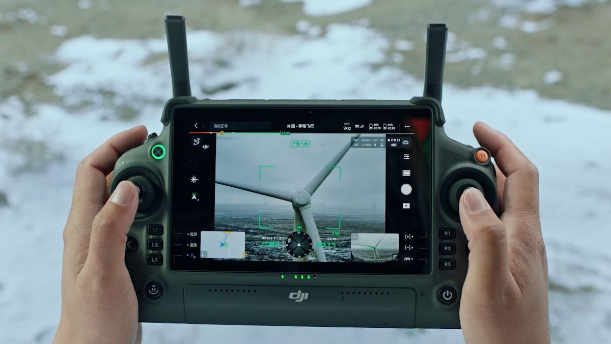 DJI RC Plus smart controller held in hands showing flight controls