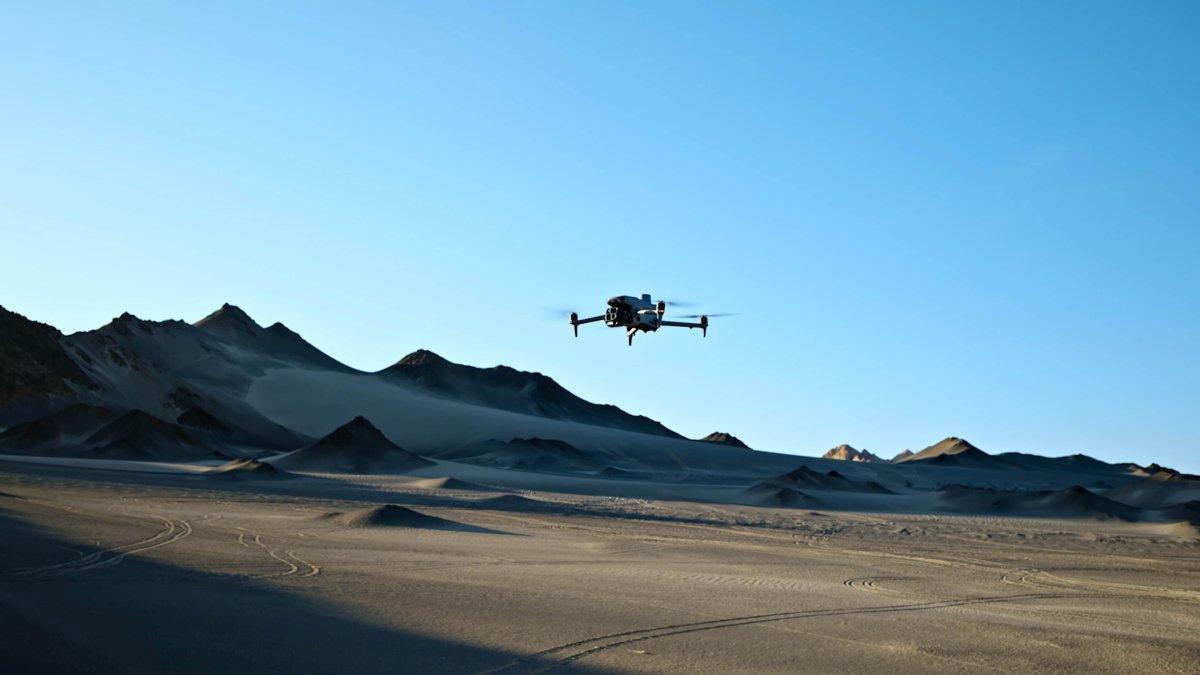 DJI Matrice enterprise drone flying in clear blue sky over mountains